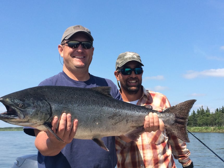 Mission Lodge Fishing Report holding up a cracking king salmon on a bright sunny day in alaska