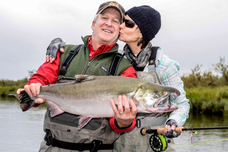 lady angler kissing her partner as he holds a nice salmon from the goodnews river lodge