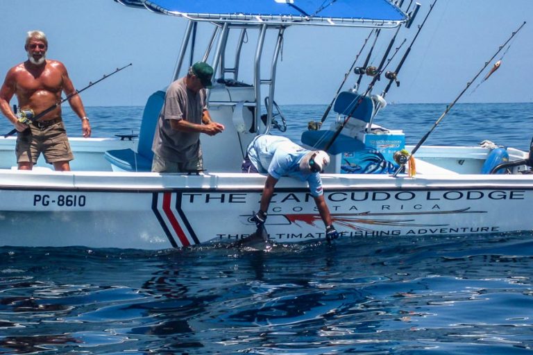 person leaning over boat with fish