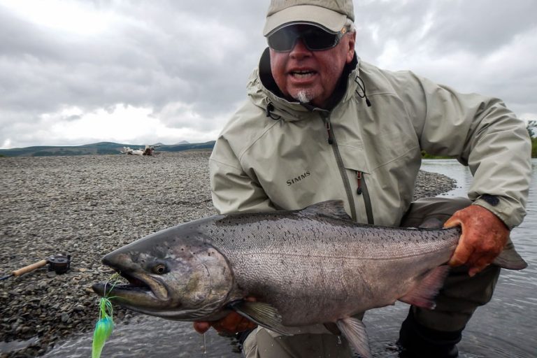 Picture of customer with a king salmon with a green fly hanging from its mouth