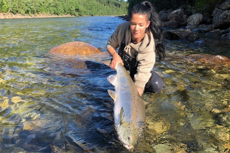 Woman fly fishing for huge salmon