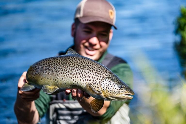 custoimer with flat cap on holding up a atlantic salmon for the camera