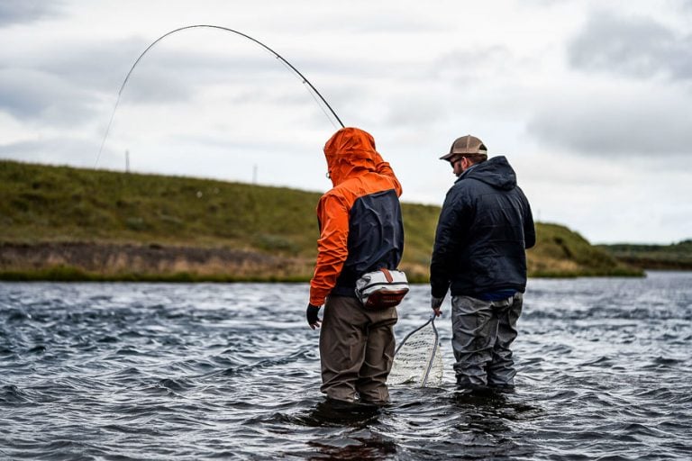 Guide helping customer land a fish