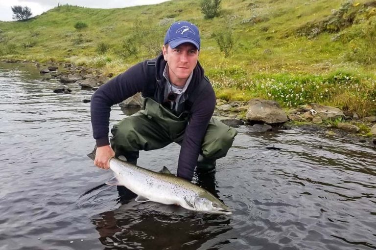 customer in blue hat returning a salmon to the west ranga river iceland