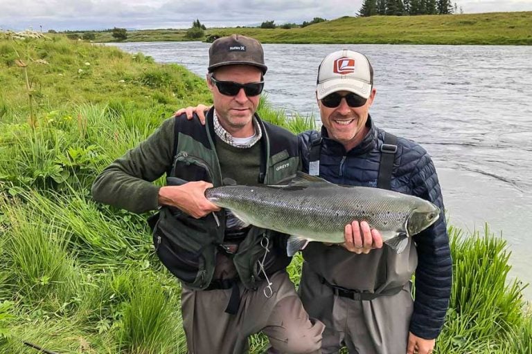 customer and guiding laughing holding up a nice Atlantic Salmon